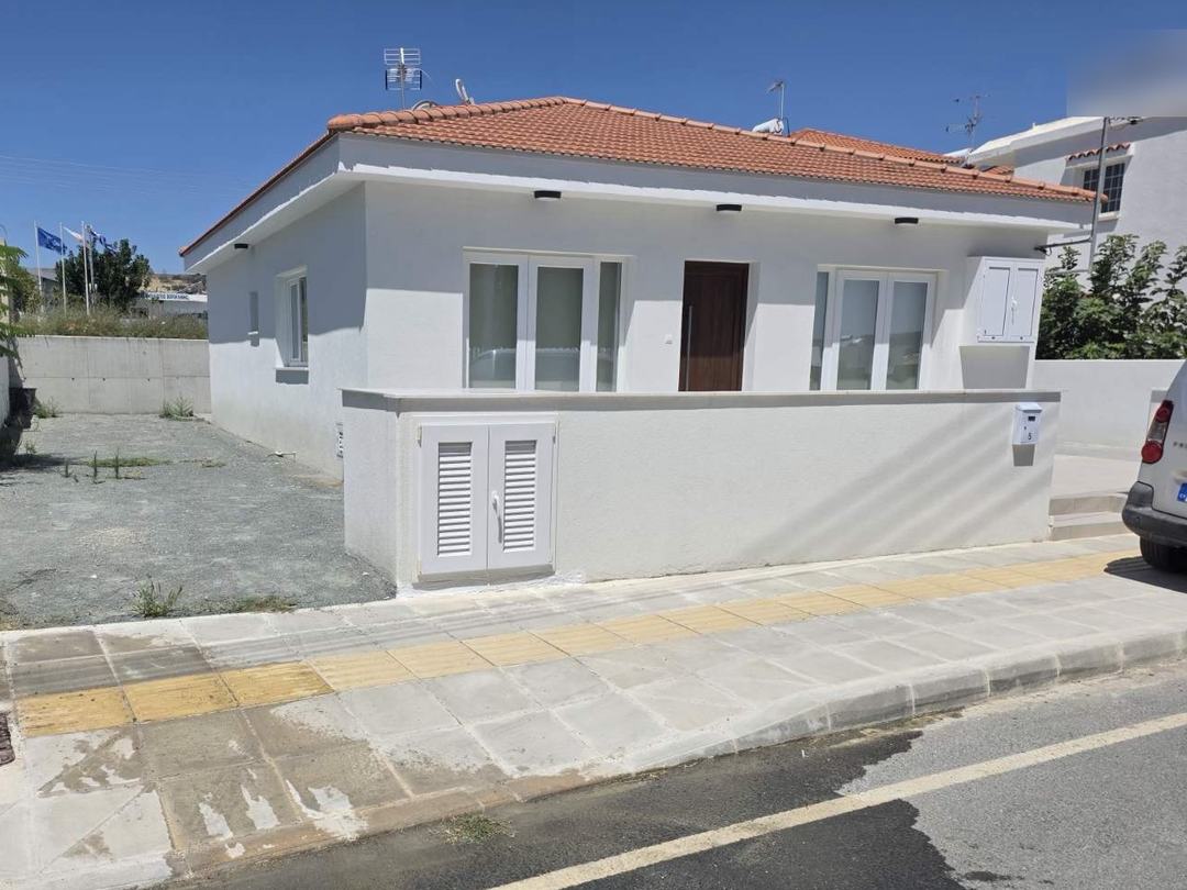 Ολοκληρωμένη ισόγεια κατοικία με λευκή πρόσοψη, κεραμοσκεπή και μάντρα στον δρόμο.